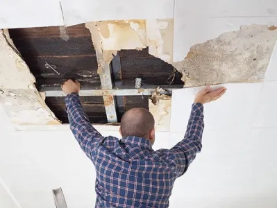 Ouvrier ouvrant un plafond pour effectuer des travaux de rénovation ou de maintenance dans un bâtiment.
