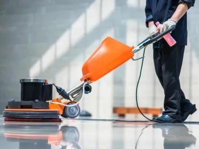 Agent d’entretien utilisant une machine monobrosse pour nettoyer un sol intérieur brillant.